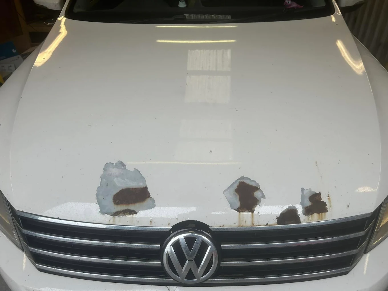 White Volkswagen bonnet with rust and paint damage before repair