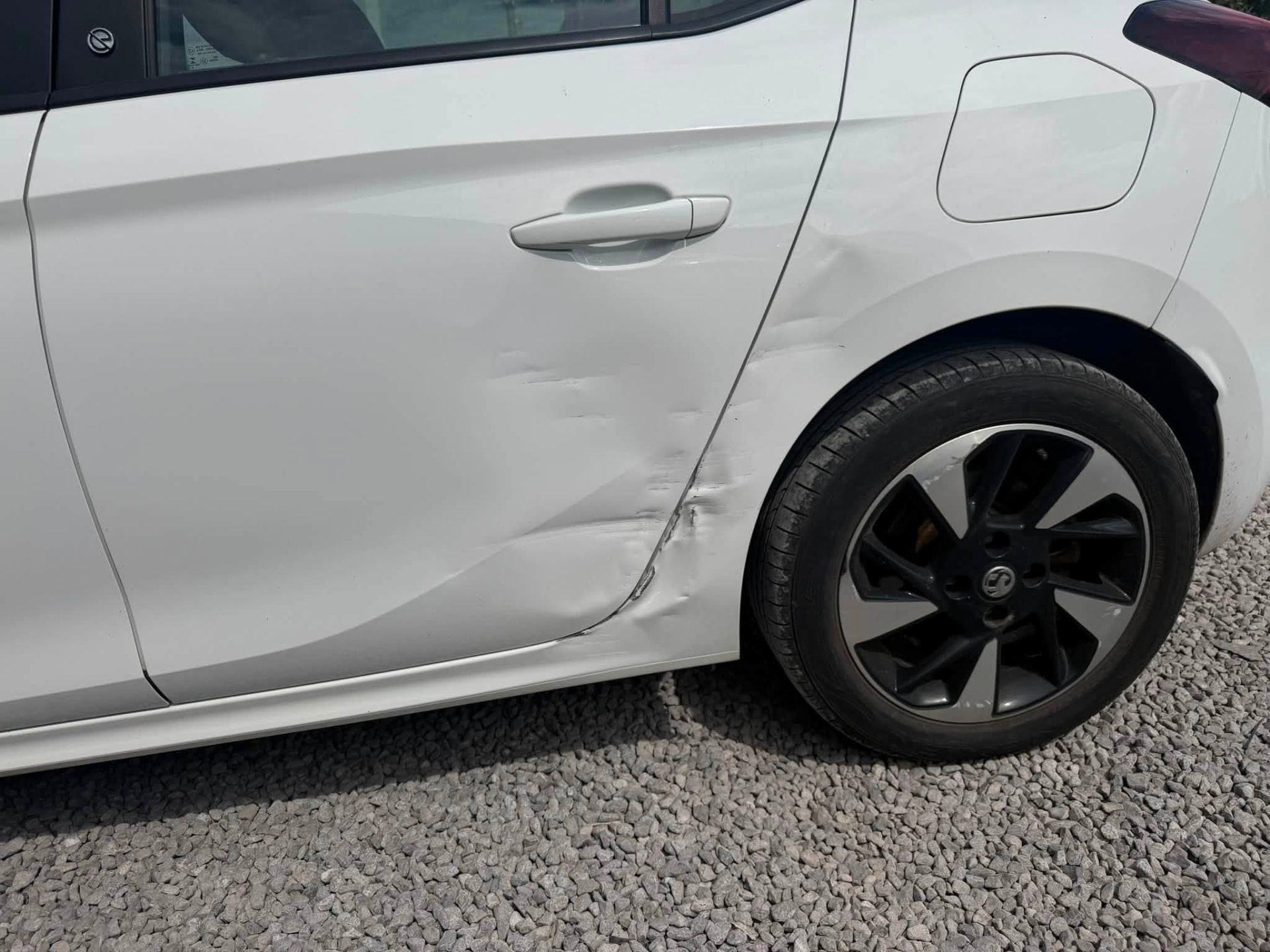White Vauxhall with damaged rear door and quarter panel before repair