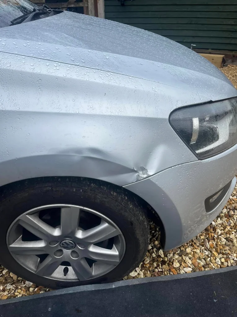 Silver Volkswagen with dented front wing before repair