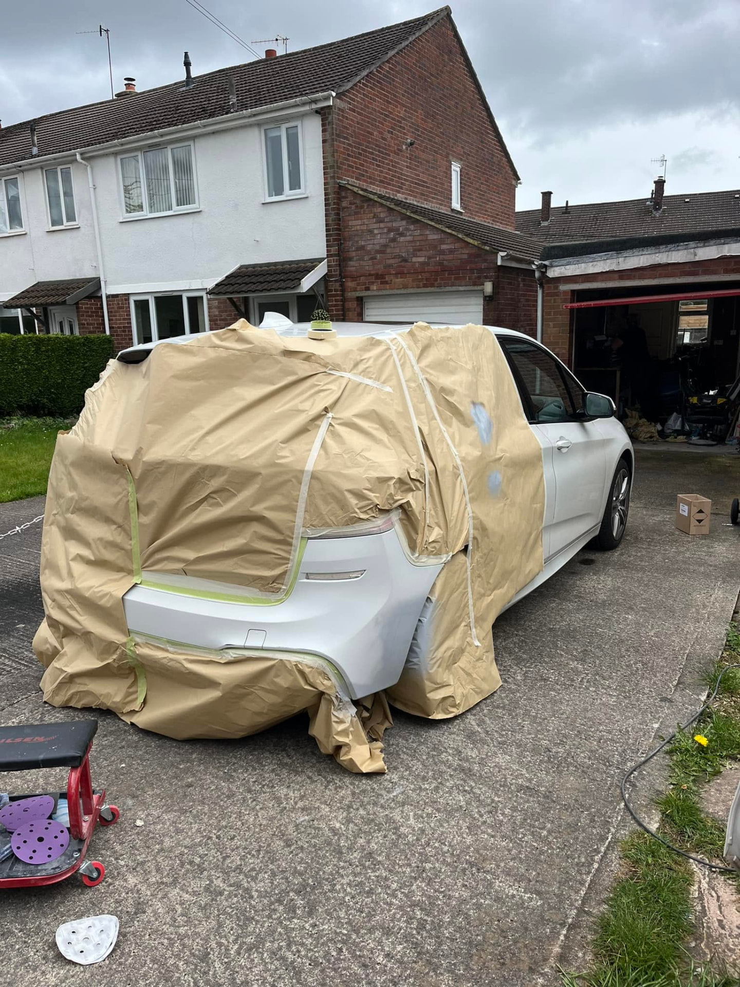 White car masked and sanded for bodywork preparation in the workshop